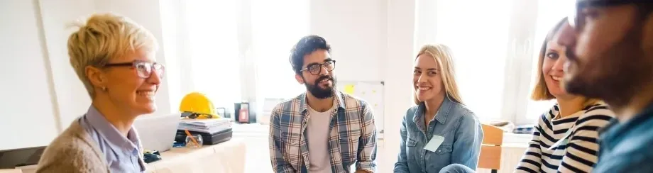 A man with glasses and beard sitting in front of another man.