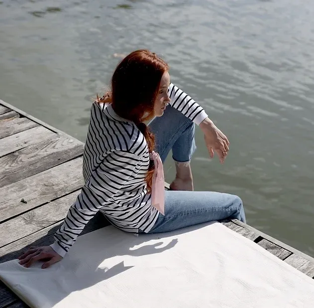 A woman sitting on the edge of a dock.